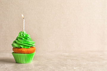 Delicious birthday cupcake with candle on light background