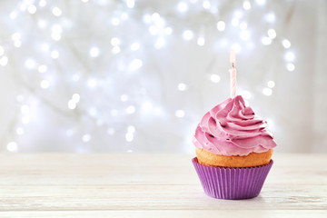 Delicious birthday cupcake with candle on table against blurred background
