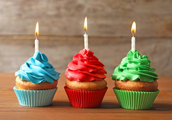 Delicious birthday cupcakes with candles on table