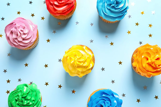 Flat lay composition with colorful birthday cupcakes on color background