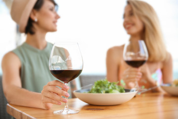 Young women with glasses of wine at table