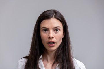 Portrait of young long-haired astonished woman