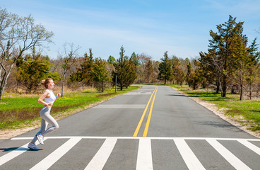 Fitness woman running on crosswalk - obrazy, fototapety, plakaty