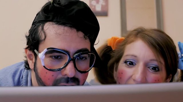 An odd couple (actors in character as kids): a guy and a girl on the bed, watching porn movies on a laptop, feeling the urge to vomit as it's not what they expected. Funny bizarre detail shot.

