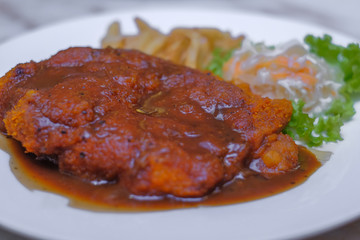 Chicken chop with vegetable and black pepper sauce in plate over dining table