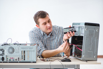 Young technician repairing computer in workshop