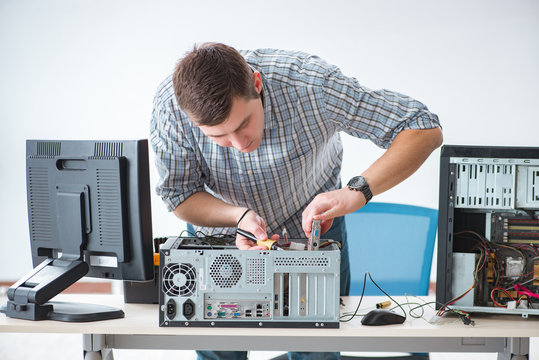 Young technician repairing computer in workshop