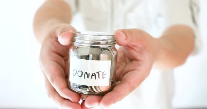 Hand holding donation money jar to invite and encourage for helping other , charity and help giving money concept , 4K Dci resolution