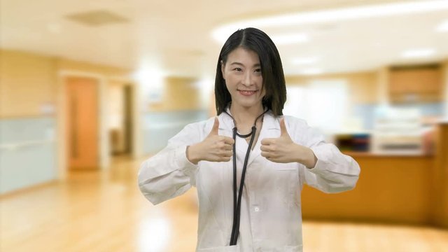 Asian female doctor showing thums up in hospital hallway wards