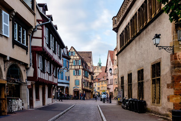 Fototapeta na wymiar Gorgeous cobbled street in Colmar, Alsace, with the Colmar Cathedral in the background