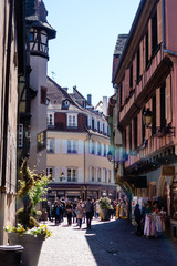 Fototapeta na wymiar Gorgeous cobbled street in Colmar, Alsace, with people walking around during spring.