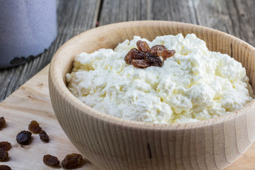 Homemade curd in a wooden bowl with raisins