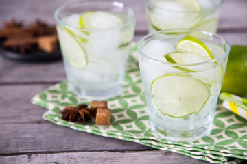 homemade lemonade with lime, anise, cinnamon and ice on a wooden background