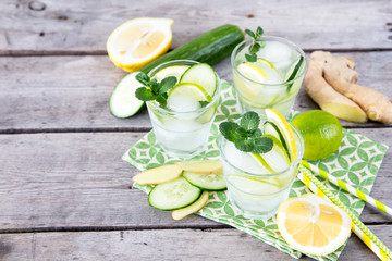 homemade lemonade with lime, mint, ginger, cucumber and ice on a wooden background