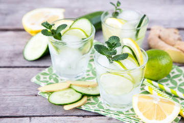 homemade lemonade with lime, mint, ginger, cucumber and ice on a wooden background