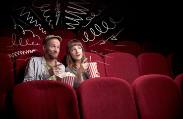 Young cute couple sitting in cinema, and eating popcorn while watching movie with doodle graphics