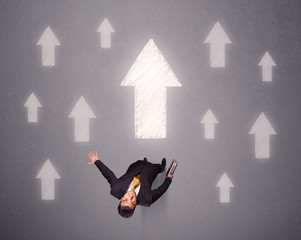 Young contemplating businessman stands in front of white arrows