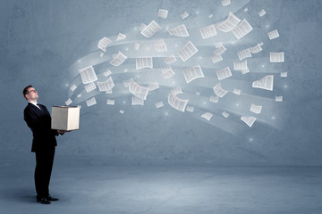Office documents, contracts, papers flying out of cardboard box being held by a young business worker concept.