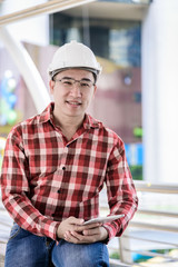 Asian business and engineer man with red scott shirt has planning and working for design buiding and city.