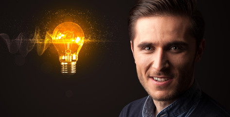 Portrait of a young businessman with a lightbulb next to him on a dark background