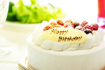 いちごとブルーベリーの乗ったバースデーケーキとピンクの飲物とグリーンサラダ