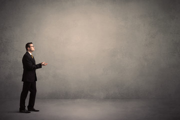 Obraz premium Caucasian businessman standing in front of a grunge, blank wall