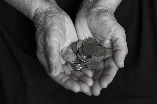 Old woman's hands, grandmother's hands with coins in handfuls, close - up, time concept, generational change black and white
