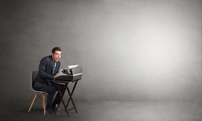 Man working hard on a typewriter in an empty space
