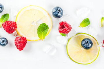Healthy organic summer food and drink concept, selection of fresh fruit and berries, lime lemon raspberry blueberry pattern on white background copy space above top view