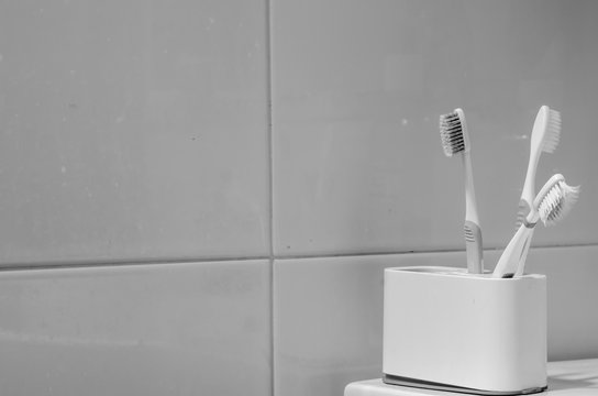 Black and white toothbrushes in box on toilet table.