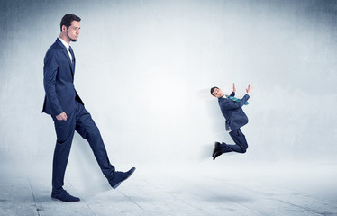 Big businessman kicking small businessman who is flying away with his briefcase on his hand
