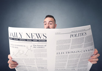 Young smart businessman reading daily newspaper