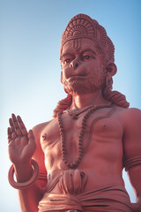 The bottom view on a huge statue of red Hanuman with the raised hand in blessing gesture.