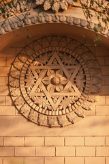 Old bas-relief on a temple wall - a Hindu six-pointed star, and blooming flower in a centre of composition, in beams of the evening sun.