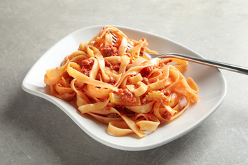 Plate with delicious pasta bolognese on grey background