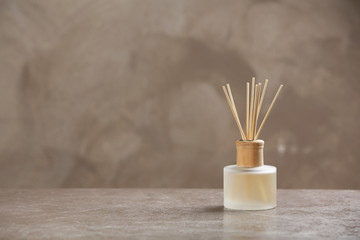 Aromatic reed freshener on table against grey background - obrazy, fototapety, plakaty