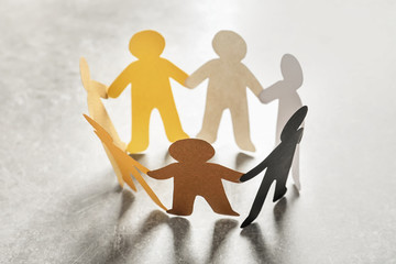 Paper people holding hands on light background. Unity concept