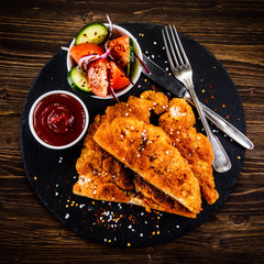 Fried pork chop with vegetables on wooden background