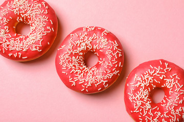 Delicious glazed doughnuts on color background, top view