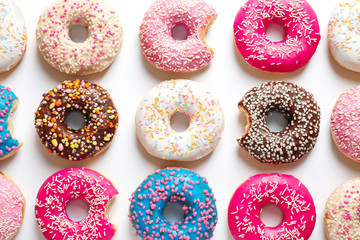 Delicious doughnuts with sprinkles on light background, top view