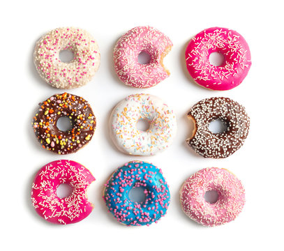 Delicious doughnuts with sprinkles on light background, top view