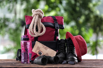 Composition with backpack and camping equipment on table against blurred background
