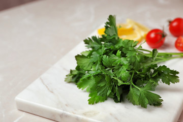 Stone board with fresh green parsley on table, closeup