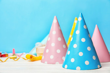 Birthday party caps on table against color background