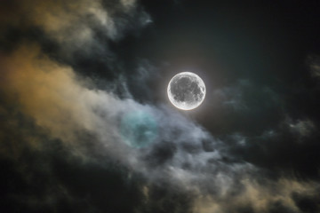 Fototapeta na wymiar full night moon shines alone in sky clouds
