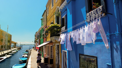 Female tourists go shopping in colorful street of Burano island in Venice Lagoon