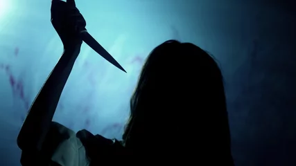 Foto op Plexiglas Bloody dark-haired murderer stabbing victim with knife, darkness and horror © motortion