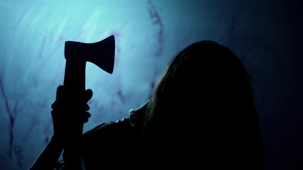 Possessed woman holding bloody ax and looking at victim, nightmarish scene