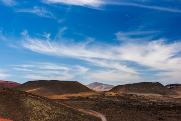 Volcanic crater in the Timanfaya National Park under a blue sky with clouds. Lanzarote, Canary Islands, Spain.