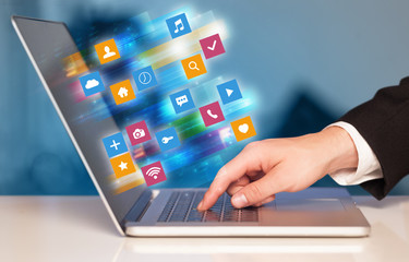 Hand using laptop with colorful fast moving application icons and symbols concept
